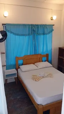 a bedroom with a bed with a blue curtain at Hotel Paradise in Isla Fuerte