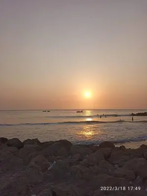 a sunset on a beach with people in the water at APARTAMENTO CON VISTA AL MAR CARIBE PISO 19 - Espectacular in Cartagena de Indias