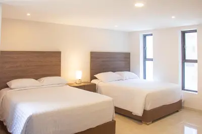 two beds in a hotel room with white sheets at Edificio Casa Tabor in Barranquilla