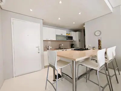 a kitchen with a wooden table and white chairs at Morros 3 Apartamentos de Lujo in Cartagena de Indias