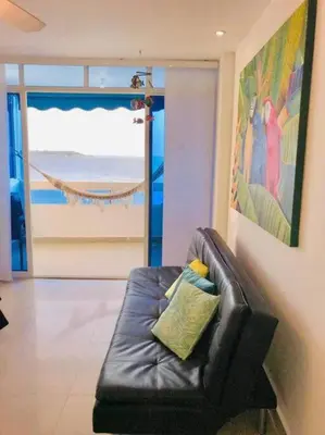 a black leather couch in a living room with a window at Hermoso apartamento con vista al mar in Cartagena de Indias