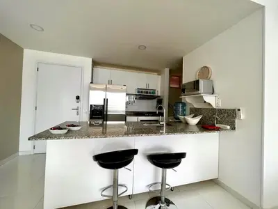 a kitchen with a counter and two stools in it at Hermoso apartamento familiar /acceso directo a la playa. Morros 3 in Cartagena de Indias