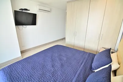 a bedroom with a blue bed and a tv at Toscana Suite 2205 in Cartagena de Indias