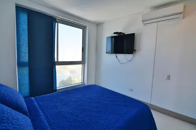 a bedroom with a blue bed and a window at Toscana Suite 2205 in Cartagena de Indias