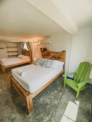 a bedroom with a bed and a green chair at Mamallena Beachside Rincon del Mar in Rincón