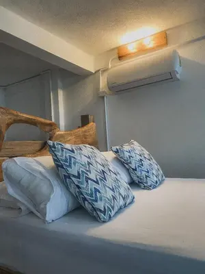 a bed with blue and white pillows on it at Mamallena Beachside Rincon del Mar in Rincón
