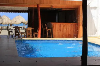 a swimming pool with chairs and umbrellas and a restaurant at Cabaña Yalis SAS in Cartagena de Indias