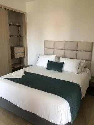 a bedroom with a large bed with white sheets and pillows at BUENAVISTA PLAZA APARTA HOTEL in Barranquilla