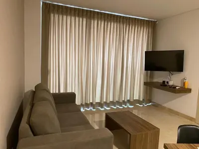 a living room with a couch and a flat screen tv at BUENAVISTA PLAZA APARTA HOTEL in Barranquilla