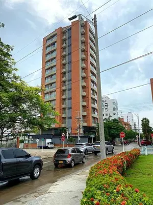 a parking lot with cars parked in front of a tall building at BUENAVISTA PLAZA APARTA HOTEL in Barranquilla