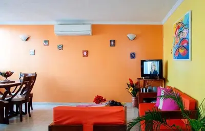 a living room with an orange wall and a television at II-Nice and cozy 2 bedroom Apt BOCAGRANDE in Cartagena de Indias