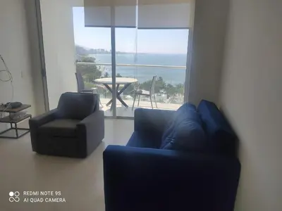 a living room with a couch and a chair and a large window at Edificio Sierra Beach Resort Pozos Colorados vista y salida al mar in Santa Marta