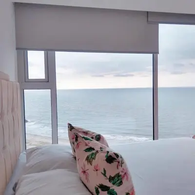 a bed with a pillow in front of a window at Pent House 450 mts 360 front ocean view playa azul in Cartagena de Indias