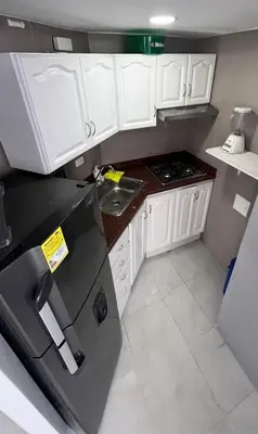 a small kitchen with white cabinets and a black refrigerator at Vista Playa in Cartagena de Indias