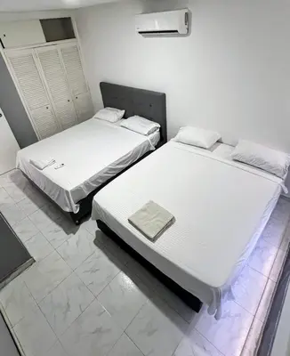 two beds in a room with white walls at Vista Playa in Cartagena de Indias