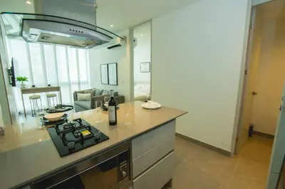 a kitchen with a stove top oven next to a living room at Suite de lujo Distrito 90 in Barranquilla