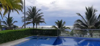 a swimming pool with palm trees and the beach at Apartamento Morros vitri 214 zona norte in Cartagena de Indias