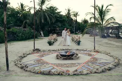 a bride and groom standing in front of a fire pit at Fenix Beach Cartagena in Tierra Bomba