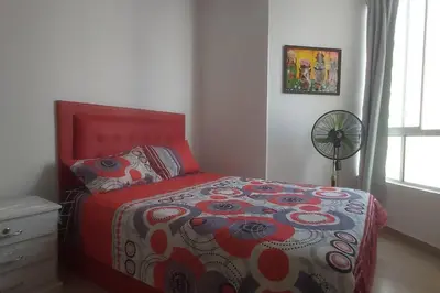 a bedroom with a bed with a red headboard and a fan at Hermoso apartamento, Cartagena, amoblado, cómodo. in Cartagena de Indias