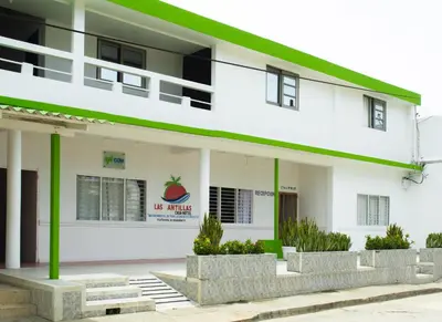 a white building with a green roof at Casa Hotel Las Antillas in Tolú