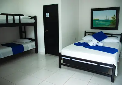 a bedroom with two bunk beds with blue and white sheets at Casa Hotel Las Antillas in Tolú