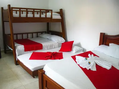 a bedroom with two bunk beds with red and white sheets at Casa Hotel Las Antillas in Tolú