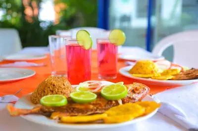a table with plates of food and drinks on it at Casa Hotel Las Antillas in Tolú