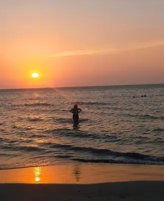 a person standing in the ocean at sunset at Cabaña El Faro in Tubará
