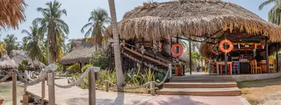 a restaurant with a straw hut with a staircase at Múcura Club Hotel in Isla Mucura