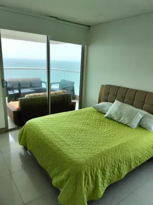 a bedroom with a green bed and a balcony at Apartamento El Laguito Cartagena in Cartagena de Indias