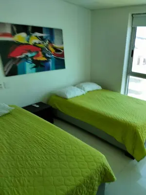 a bedroom with two beds and a painting on the wall at Apartamento El Laguito Cartagena in Cartagena de Indias