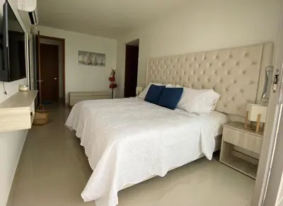 a bedroom with a large white bed with blue pillows at Paraíso frente al Mar Caribe en Cartagena. in Cartagena de Indias