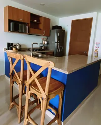 a kitchen with a blue island with two wooden bar stools at Paraíso frente al Mar Caribe en Cartagena. in Cartagena de Indias
