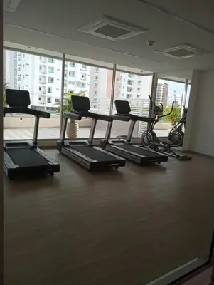 a gym with treadmills and ellipticals in front of a window at Linda suite in Barranquilla