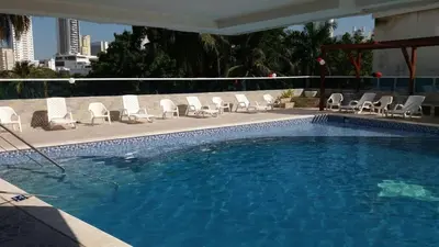a swimming pool with white chairs and a bunch ofitures at Apartamento en Cartagena Colombia in Cartagena de Indias