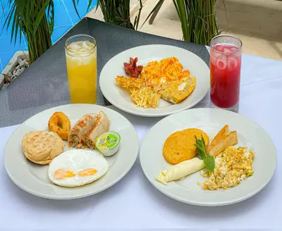 three plates of breakfast food on a table with drinks at Hotel El Marqués De Manga in Cartagena de Indias