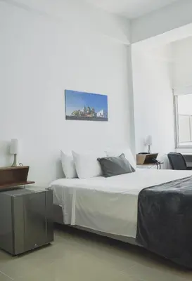 a white bedroom with a bed with white sheets at Hotel El Marqués De Manga in Cartagena de Indias