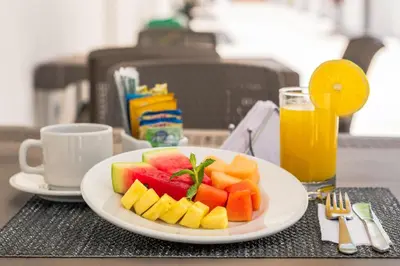 a plate of fruit on a table with a glass of orange juice at Hotel El Marqués De Manga in Cartagena de Indias