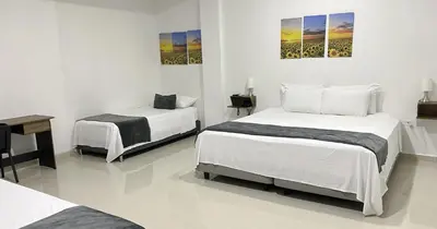 a bedroom with two beds and a desk and a table at Hotel El Marqués De Manga in Cartagena de Indias