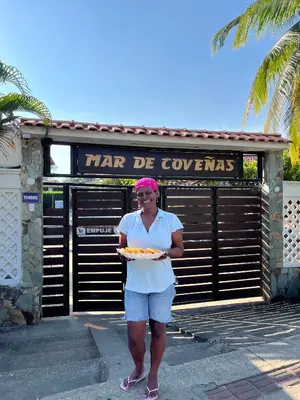 a woman holding a plate of food in front of a building at Cabaña en coveñas in Coveñas