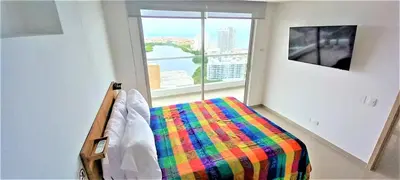a bedroom with a bed with a colorful blanket and a window at P23 Brand New high floor, few blocks to walled city steps to beach in Cartagena de Indias