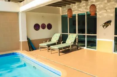a room with a pool and two chairs next to at Casa Arcoíris: Espectacular casa en Cartagena con Acceso directo a la Playa in Cartagena de Indias