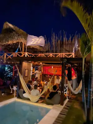 a group of people sitting in hammocks next to a pool at KokohauBungalows in Santa Veronica