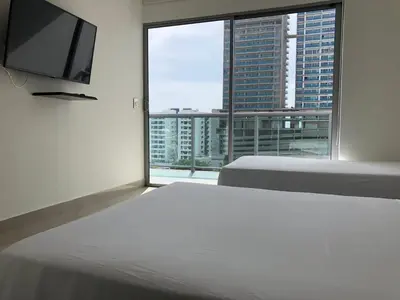 a bedroom with two beds and a flat screen tv at Edificio NUEVO DE LUJO CARTAGENA BOCAGRANDE in Cartagena de Indias