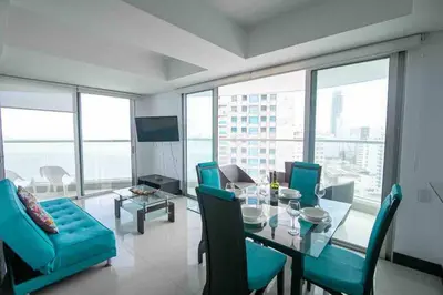 a dining room with a glass table and blue chairs at Apartamento Bocagrande Vista al Mar Piso 21 in Cartagena de Indias