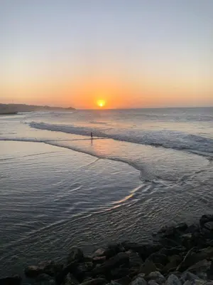 a person walking on the beach at sunset at Hotel Villa Mary Apartaestudios playa in Puerto Colombia