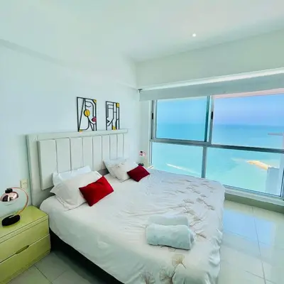 a white bedroom with a large bed with red pillows at Apartamento Cartagena con vista al mar in Cartagena de Indias