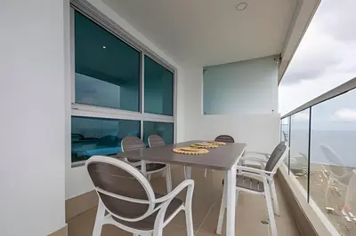a dining room with a table and chairs and large windows at Laurdhomes Lujoso Apto Piso 28 frente al mar, 2BTH in Cartagena de Indias