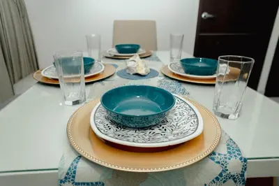 a table with plates and glasses and a bowl on it at Hermoso apartamento. Cerca del mar. in Santa Marta