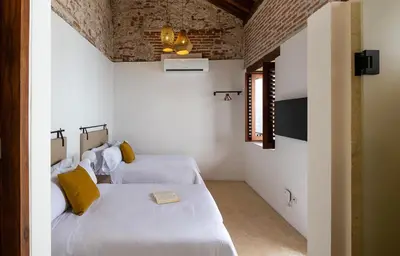 two beds in a room with white walls at Hotel Voilá Getsemaní in Cartagena de Indias